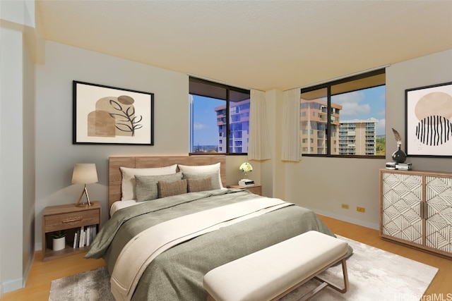 bedroom featuring a city view, baseboards, and wood finished floors