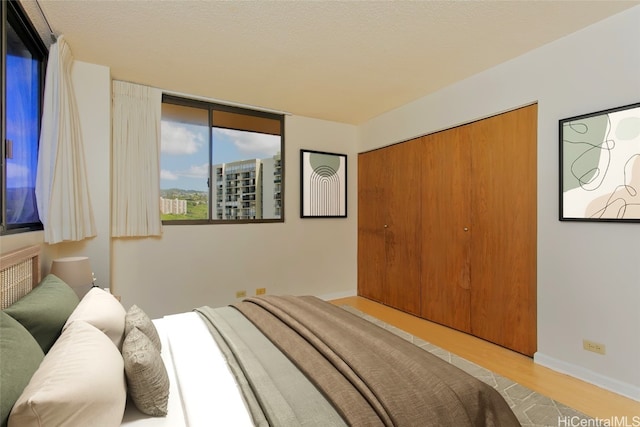 bedroom with wood finished floors, baseboards, and a closet