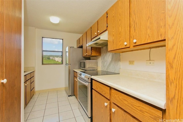 kitchen featuring brown cabinets, under cabinet range hood, stainless steel appliances, light countertops, and light tile patterned floors