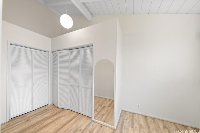 unfurnished bedroom featuring a closet, vaulted ceiling with beams, wood ceiling, and light hardwood / wood-style flooring