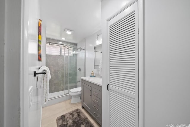 bathroom with tile patterned flooring, vanity, toilet, and walk in shower