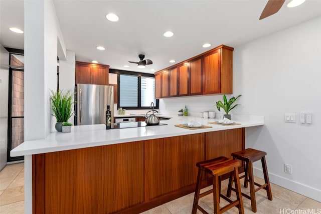 kitchen with light countertops, recessed lighting, a peninsula, freestanding refrigerator, and a ceiling fan