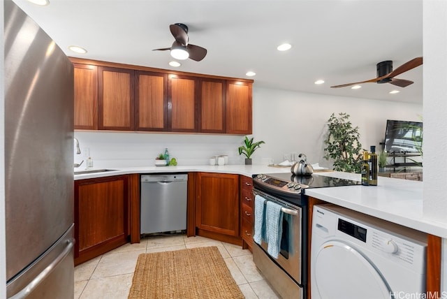 kitchen with washer / clothes dryer, appliances with stainless steel finishes, a ceiling fan, and light countertops