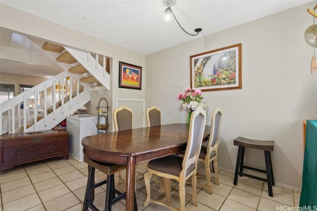 tiled dining room featuring a textured ceiling