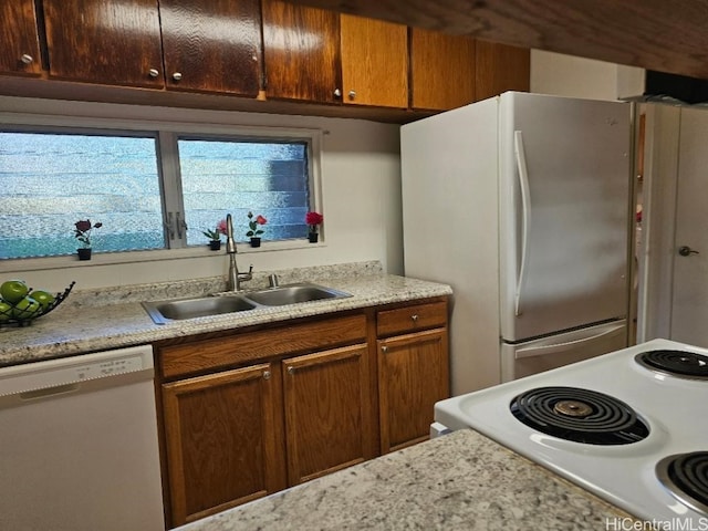 kitchen featuring brown cabinetry, white appliances, light countertops, and a sink