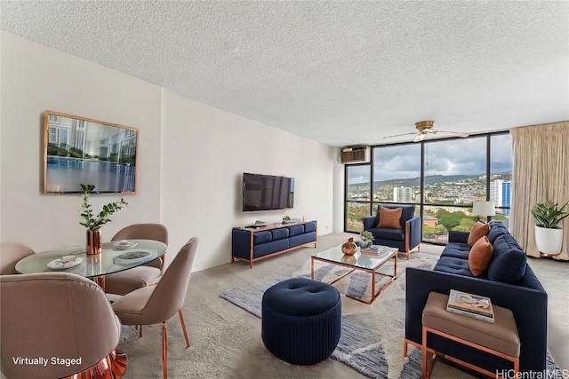 carpeted living room featuring expansive windows, ceiling fan, a wall mounted AC, and a textured ceiling