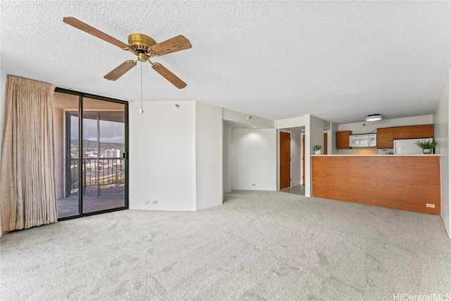 unfurnished living room with floor to ceiling windows, light carpet, ceiling fan, and a textured ceiling