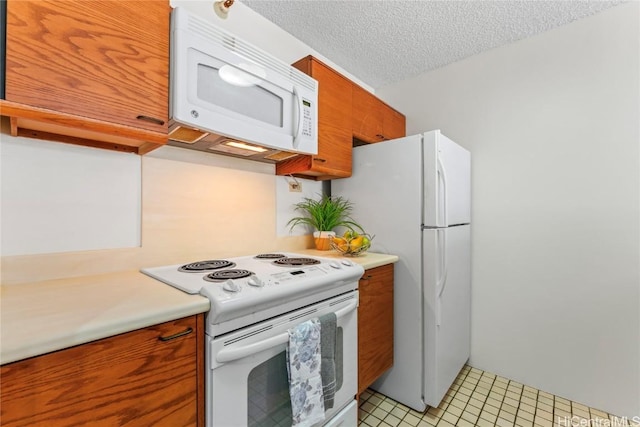 kitchen featuring white appliances, a textured ceiling, and light tile patterned floors