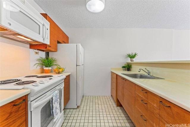 kitchen featuring sink, white appliances, light tile patterned floors, and a textured ceiling