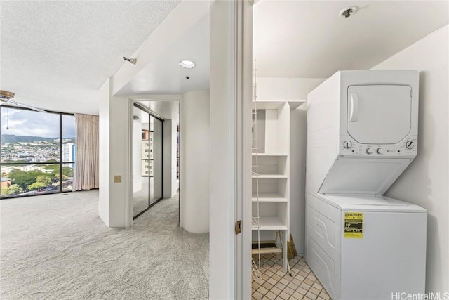 laundry room with light colored carpet, stacked washer and clothes dryer, and a textured ceiling