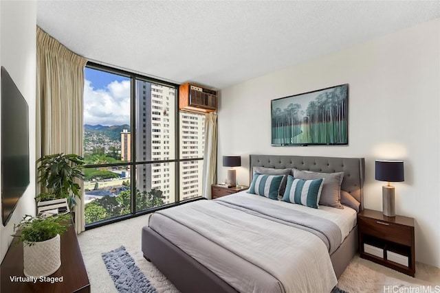 carpeted bedroom featuring a mountain view, a textured ceiling, floor to ceiling windows, and a wall mounted AC