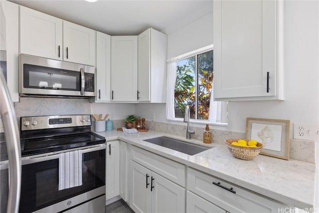 kitchen with white cabinetry, sink, light stone countertops, and appliances with stainless steel finishes