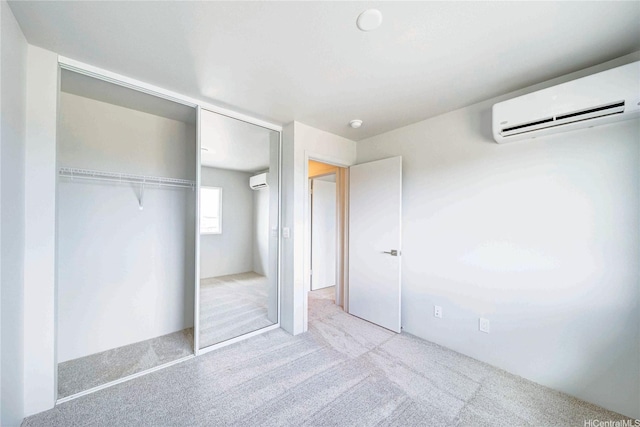 unfurnished bedroom featuring light carpet, a wall unit AC, and a closet