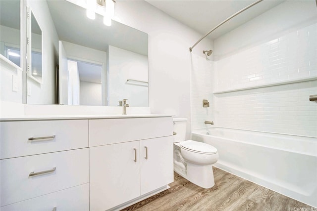 bathroom with toilet, vanity, wood finished floors, and tub / shower combination