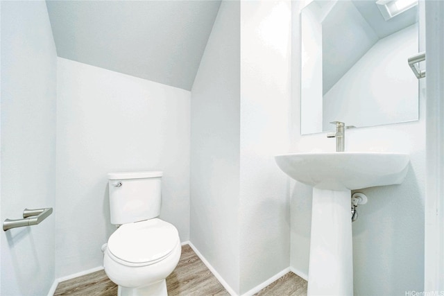 bathroom featuring toilet, wood finished floors, baseboards, and vaulted ceiling