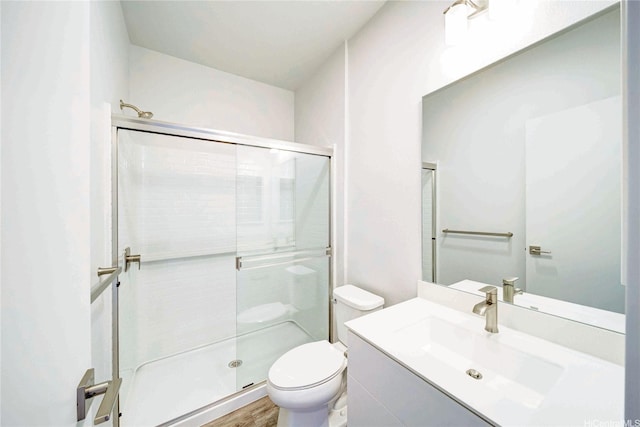 bathroom with toilet, a stall shower, wood finished floors, and vanity