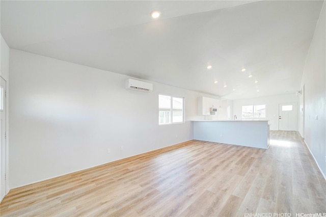 interior space featuring a wealth of natural light, light wood finished floors, and a wall unit AC