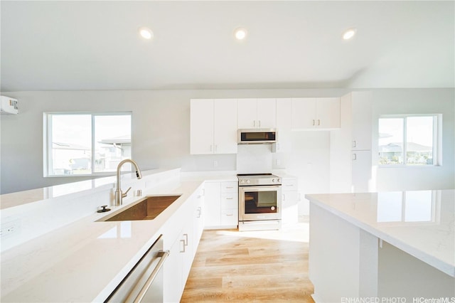 kitchen with appliances with stainless steel finishes, a sink, white cabinetry, and plenty of natural light
