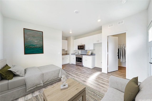 living area featuring light wood-style floors, visible vents, and recessed lighting