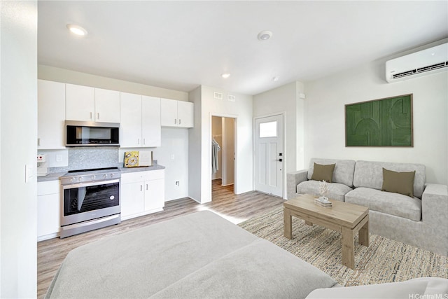 living area featuring light wood-style flooring, recessed lighting, and a wall mounted air conditioner