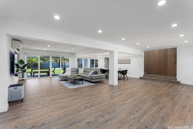 living room featuring a wall mounted air conditioner and hardwood / wood-style flooring