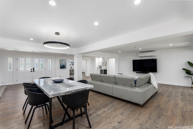 dining area with a wall mounted air conditioner and hardwood / wood-style floors