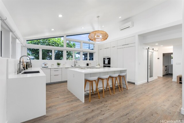 kitchen featuring pendant lighting, sink, white cabinets, a kitchen island, and a barn door