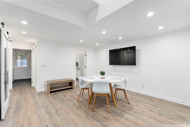 dining area with a barn door and light wood-type flooring