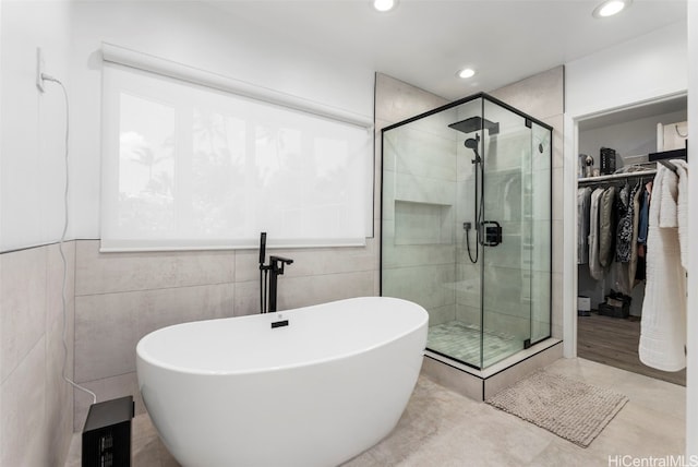 bathroom with tile walls and independent shower and bath