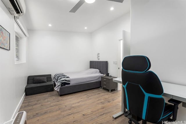 bedroom with ceiling fan, a wall mounted air conditioner, and wood-type flooring