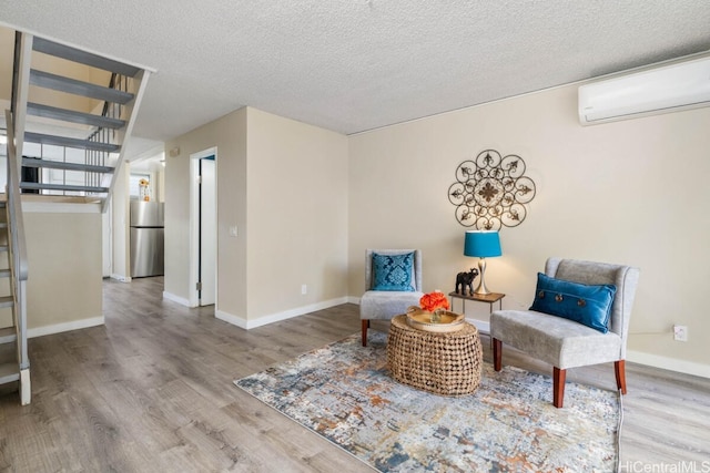 living area with a textured ceiling, stairway, wood finished floors, and a wall mounted air conditioner