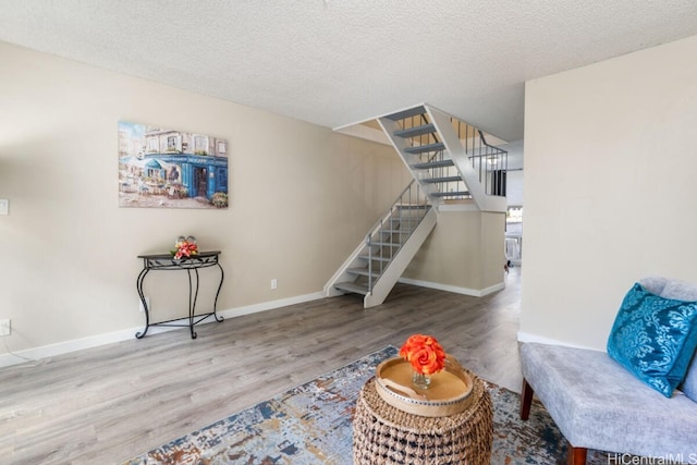 sitting room with baseboards, a textured ceiling, stairway, and wood finished floors