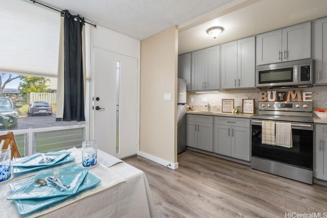 kitchen with light wood-type flooring, gray cabinets, and stainless steel appliances