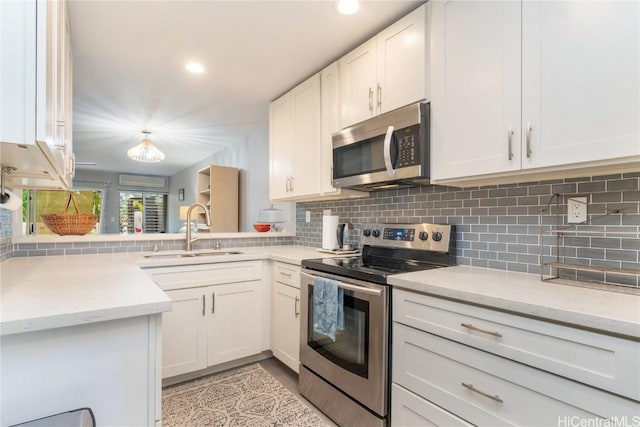 kitchen featuring tasteful backsplash, white cabinetry, sink, light stone counters, and stainless steel appliances