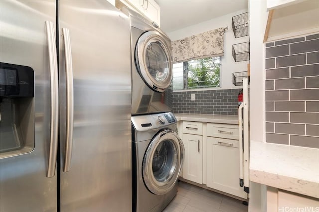 laundry room with cabinets and stacked washer / dryer