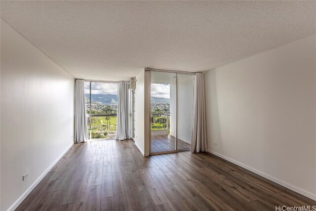 spare room featuring floor to ceiling windows, dark hardwood / wood-style flooring, and a textured ceiling