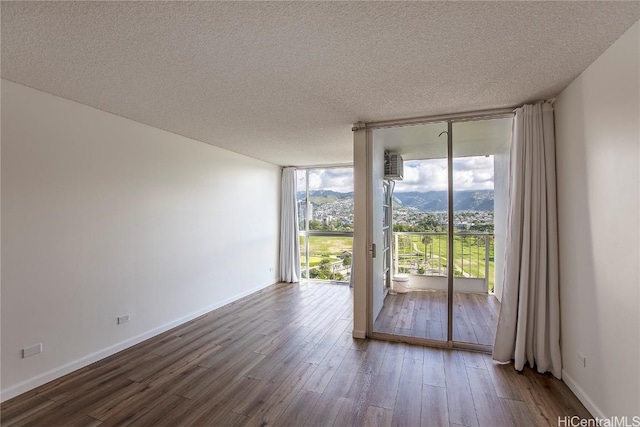 spare room with expansive windows, wood-type flooring, and a textured ceiling