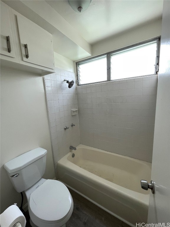 bathroom featuring tiled shower / bath combo, wood-type flooring, and toilet