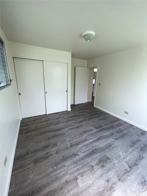 unfurnished bedroom with dark hardwood / wood-style flooring and a closet