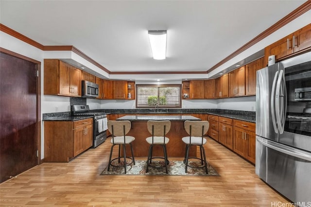 kitchen featuring stainless steel appliances, a kitchen breakfast bar, a kitchen island, and light wood-type flooring