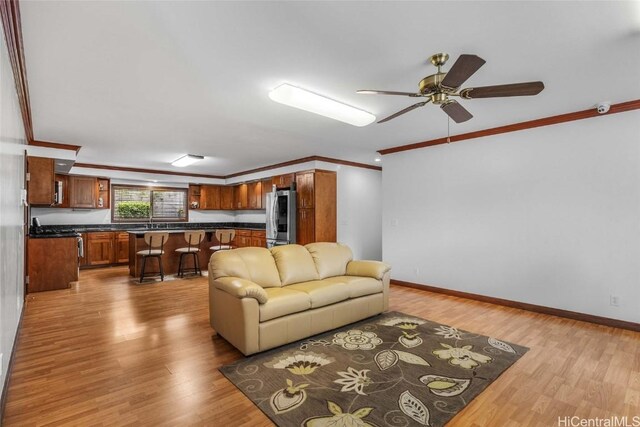 living room with crown molding, ceiling fan, and light wood-type flooring