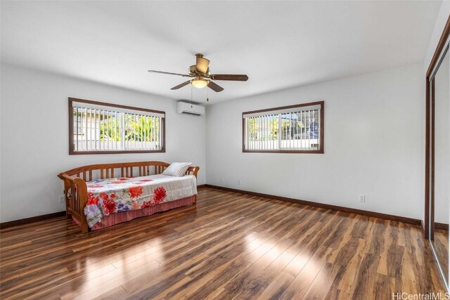 bedroom with dark hardwood / wood-style flooring, ceiling fan, and a wall unit AC