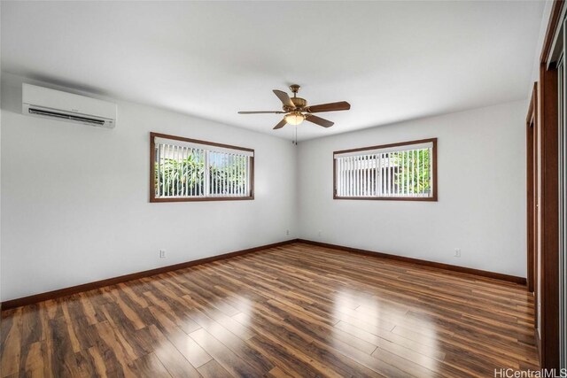 unfurnished room featuring plenty of natural light, dark wood-type flooring, a wall mounted AC, and ceiling fan