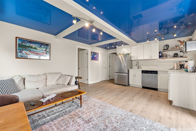 living room featuring sink, track lighting, beamed ceiling, and light wood-type flooring