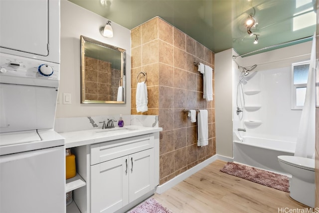 full bathroom featuring toilet, shower / bathing tub combination, vanity, hardwood / wood-style flooring, and stacked washing maching and dryer