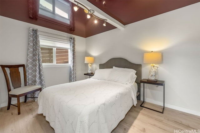 bedroom featuring light hardwood / wood-style floors and beamed ceiling