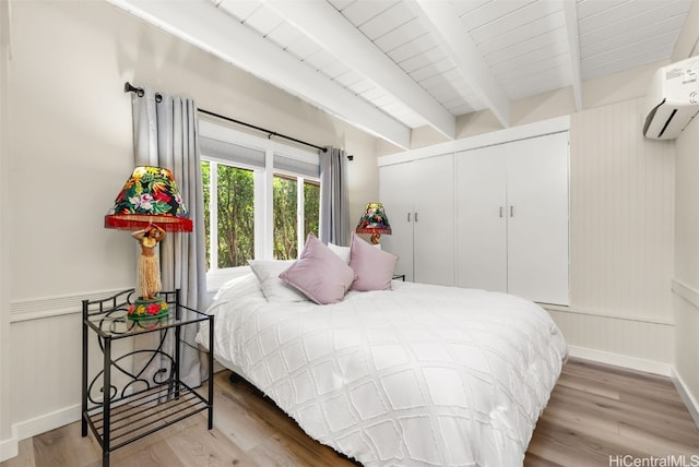 bedroom featuring hardwood / wood-style floors, beam ceiling, a closet, and a wall mounted AC