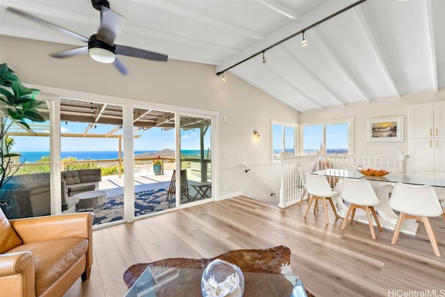 interior space featuring lofted ceiling with beams, ceiling fan, a water view, track lighting, and light wood-type flooring