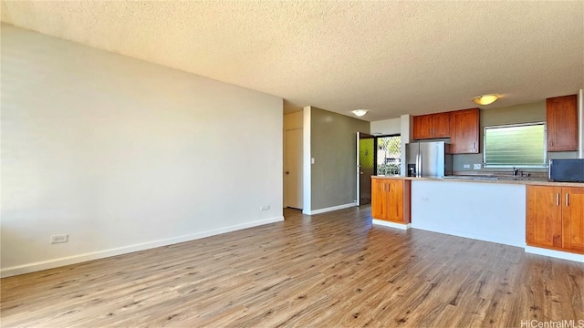 kitchen featuring stainless steel refrigerator with ice dispenser, light hardwood / wood-style floors, and a textured ceiling