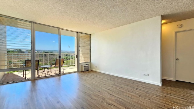 unfurnished room featuring floor to ceiling windows, hardwood / wood-style floors, and a textured ceiling